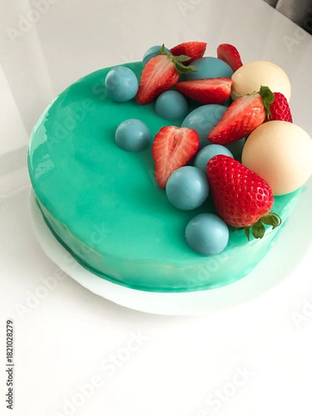 Fototapeta Modern Teal Glazed Cake with Strawberries and Chocolate Spheres. A close-up, high-angle view of a visually stunning round cake covered in a smooth, glossy teal mirror glaze.