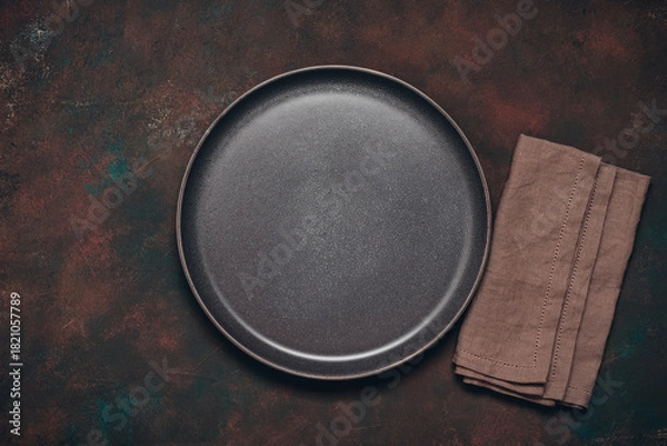 Fototapeta Empty brown plate and linen napkin on dark rusty background, top view, flat lay, copy space