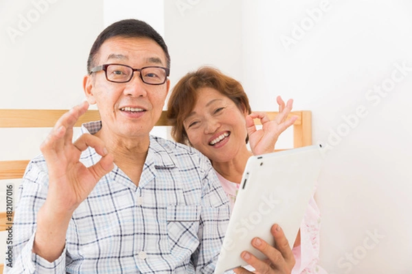Fototapeta シニア夫婦　タブレットコンピューター　ベッド