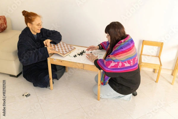 Fototapeta Two women playing chess board game enjoying leisure time