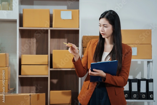 Fototapeta Asian female entrepreneurs coordinating product handover at an e-commerce office, preparing parcels for shipping logistics while collaborating professionally to manage online business operations