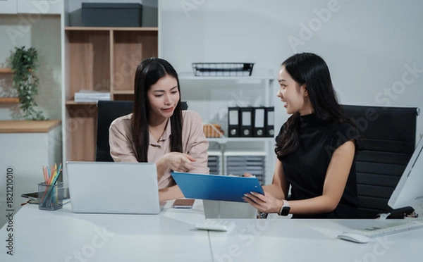 Fototapeta Asian businesswoman working at desk, analyzing data, reviewing reports, providing consultation, strategizing marketing, finance, and accounting tasks, focused, professional, organized, using laptop