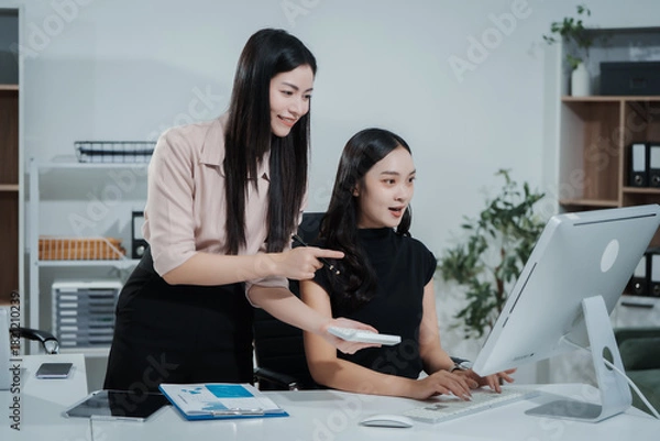 Fototapeta Asian businesswoman working at desk, analyzing data, reviewing reports, providing consultation, strategizing marketing, finance, and accounting tasks, focused, professional, organized, using laptop
