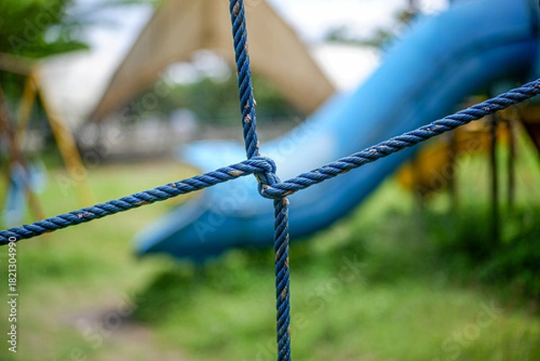 Fototapeta Closeup of blue ropes tied in a knot at a park playground setting