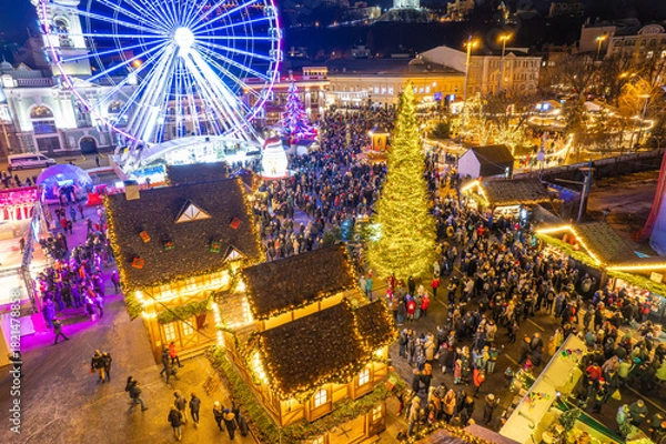 Obraz Aerial drone view of a festive Christmas market with a Ferris wheel at night.