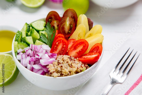 Fototapeta Healthy buddha quinoa salad bowl with tomatoes, cucumbers, red onions. On white wooden table background. Top view copy space.

