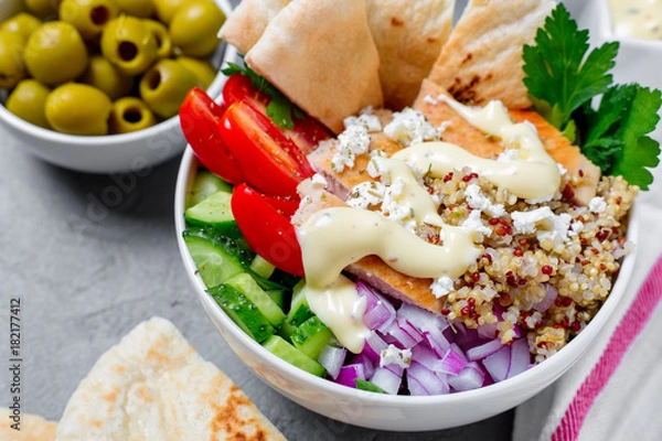 Fototapeta Healthy quinoa salad bowl with tomatoes, cucumbers, red onions chicken and feta cheese. On grey concrete background. Horizontal side view.


