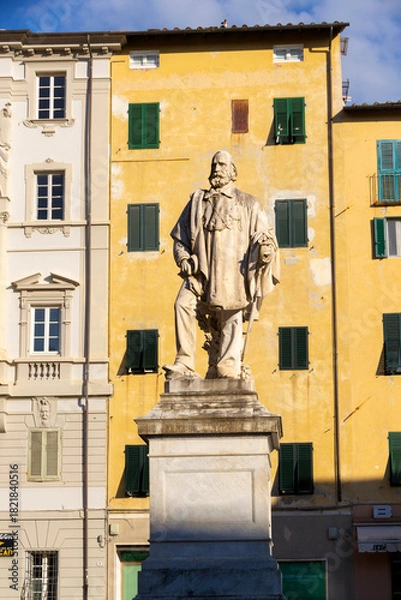 Obraz Statue Of A Revered Figure In A Sunlit Italian Town Square With Yellow Facades