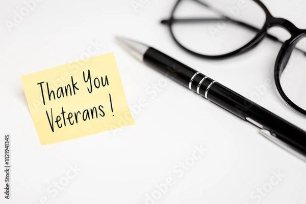 Obraz Appreciation: Yellow note "Thank You Veterans!" Symbolizing gratitude, lying next to an elegant pen and glasses on a clean, white desk top.