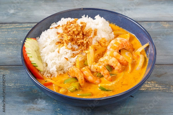 Obraz Crevettes au curry rouge thaï dans un bol bleu, cuisine thaïlandaise, fond bleu rustique
