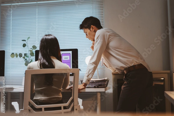 Fototapeta Two design colleagues working together in an office, brainstorming creative ideas and developing user interface for mobile application