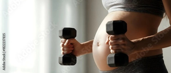 Obraz Pregnant woman exercising with dumbbells, showcasing a healthy and active lifestyle during pregnancy. Close-up view of her belly and weights, emphasizing fitness, strength, and prenatal wellness.
