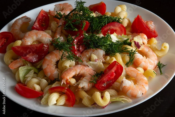 Obraz Pasta with shrimp, vegetables and herbs on a plate on a black background