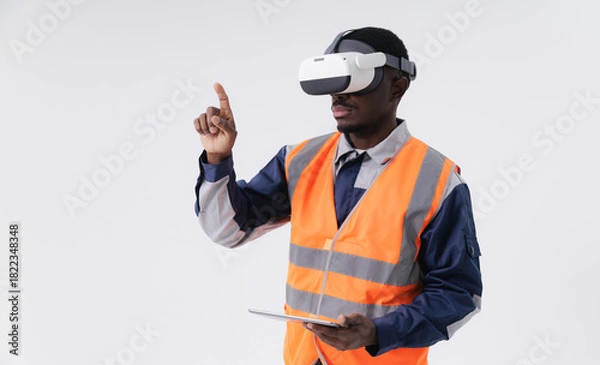 Fototapeta African male adult engineer with tablet computer using vr headset for virtual training in safety vest