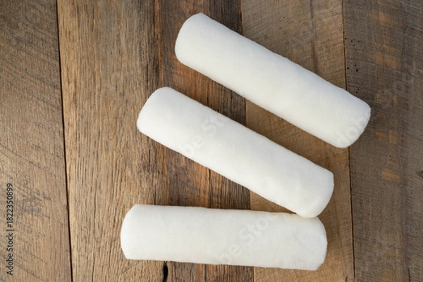 Obraz Three white woven fabric paint rollers on a wooden background.