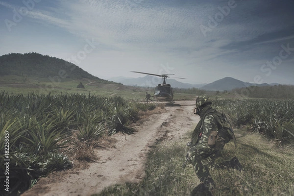Fototapeta Thai Army Helicopter is landing on the open field operation site while the soldiers are preparing to jump up.