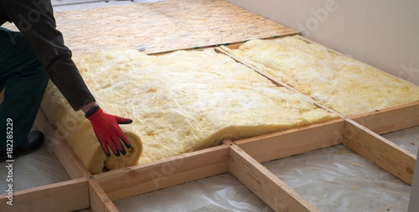 Fototapeta Work composed of mineral wool insulation in the floor, floor heating insulation , warm house, eco-friendly insulation, a builder at work