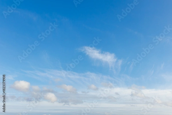 Obraz Clear blue sky with delicate cirrus streaks and scattered cumulus clouds. Soft cloud formations add texture to the serene sky, making this image ideal for nature backgrounds or weather themes.
