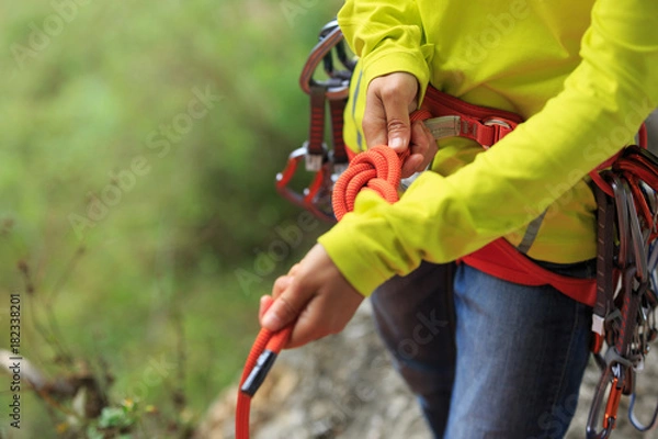 Fototapeta Сlimber wearing safety harness making a eight rope knot