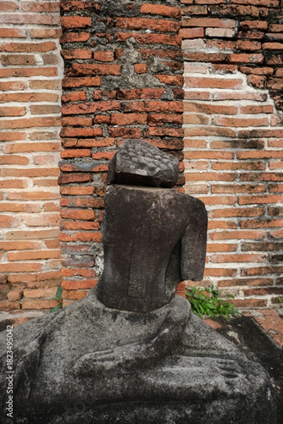 Fototapeta An ancient Buddha image remains against an ancient wall.