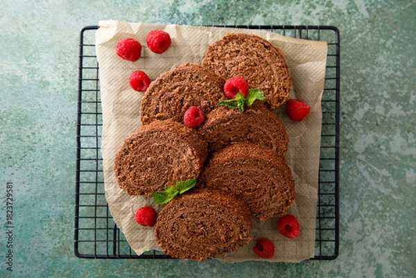 Fototapeta Dark chocolate swiss roll with raspberry