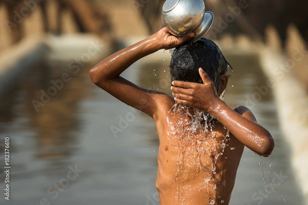 Obraz Bath in the desert.A child taking bath in watering trough or puddle in the desert, India. Water concept