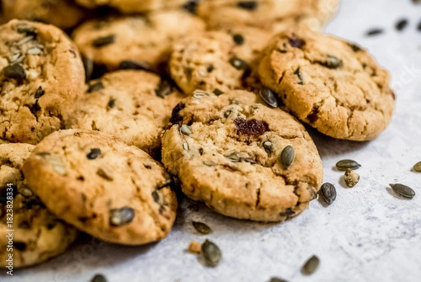 Fototapeta Golden muscovado sugar cookies studded with pumpkin seeds, arranged on a light textured surface. Ideal for baking themes, snack concepts and seasonal food content.