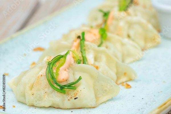Fototapeta Gyoza topped with sauce and garnished with chuka seaweed, a Chinese-style appetizer, Asian dumplings
