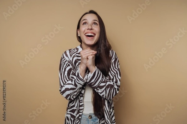 Obraz Woman smiling and expressing excitement, wearing striped jacket against a solid light background