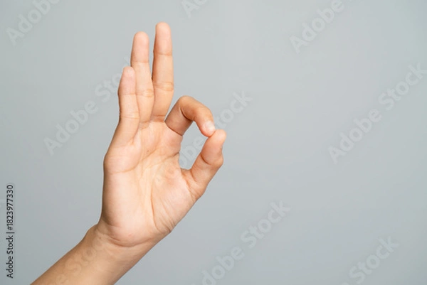 Obraz Human Hand Showing OK Gesture Sign With Thumb And Index Finger Forming Circle Against Gray Backdrop