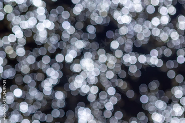Obraz Soft white bokeh lights creating an abstract, festive glow against a dark background.