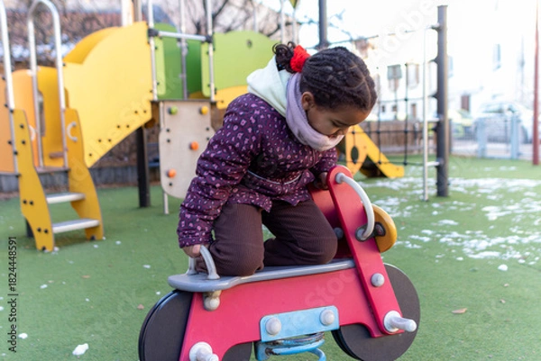 Obraz Young child enjoying playtime on a spring rider at an outdoor playground, experiencing childhood fun, development, and active leisure activities during winter