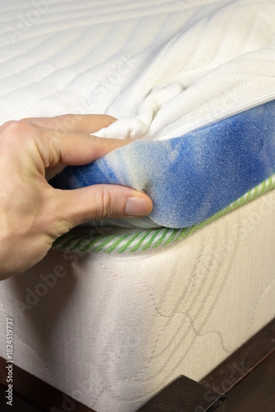 Fototapeta Hand is touching mattress inner filling. Topper mattress with a core of pressure-relieving blue gel foam. Adapts to body and leads away excess heat. Vertical photo.