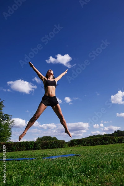Obraz The girl in the Park, jumping up on the background of clear sky.