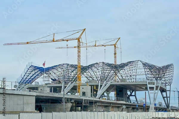 Fototapeta Rail Baltic station construction with cranes and steel roof structure in Riga, Latvia