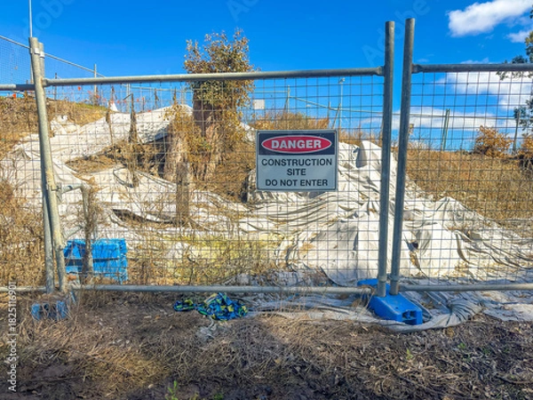 Fototapeta Photograph of a Danger Warning Sign on a fence barricade notifying people not to enter a small construction site in regional New South Wales, Australia. 