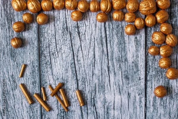 Obraz Gold nuts and gilt sticks on the background of old wooden panels, Christmas and New year background