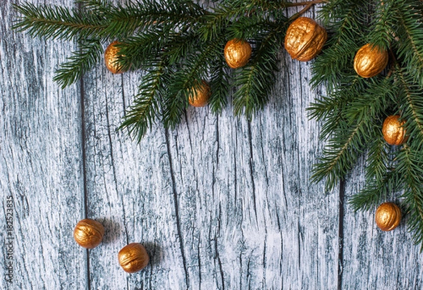 Obraz Branches of fir trees with Christmas ornaments of gilded nuts on a background of old wooden panels, Christmas background