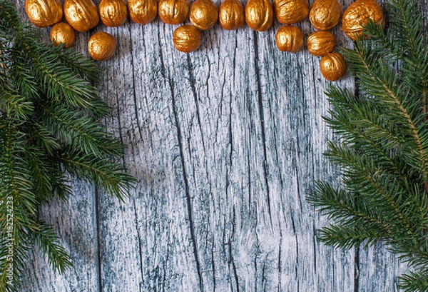 Obraz Branches of fir trees with Christmas ornaments of gilded nuts on a background of old wooden panels, Christmas background