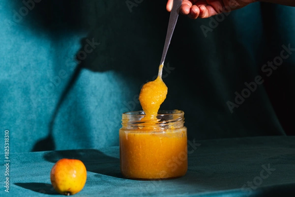 Obraz Hand scooping sweet homemade apple jam from jar
