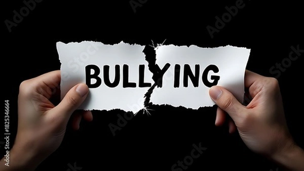 Obraz Two hands tear apart a paper with the word "bullying," symbolizing rejection of violence and support for kindness. Close-up shot with dark background and clear focus