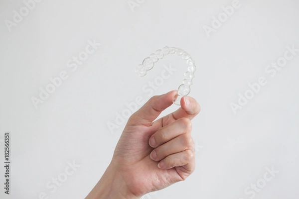 Obraz Hand holding clear invisalign braces on white background, new technology of dental equipment