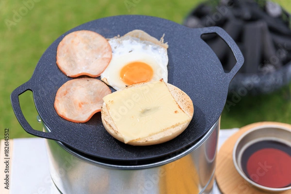 Obraz 黒いマルチグリドルと具材のクローズアップ、芝生の緑を背景に