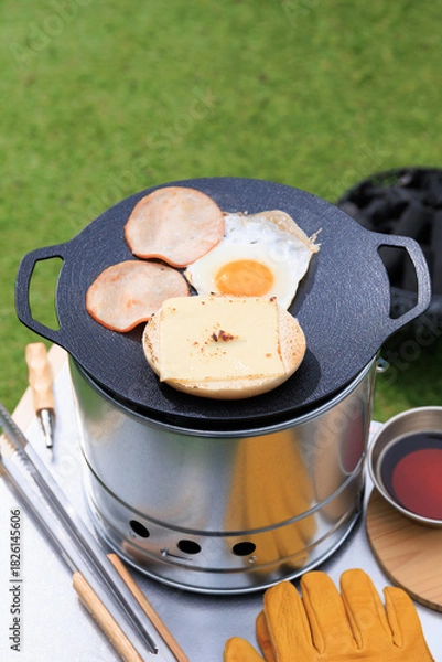 Obraz 黒いマルチグリドルと具材のクローズアップ、芝生の緑を背景に