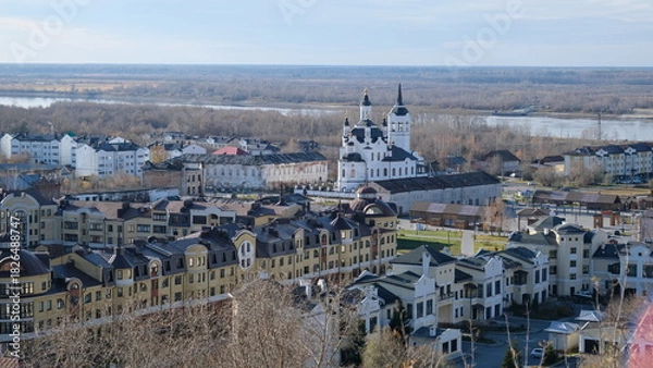 Fototapeta A view of Tobolsk from a hill. Houses, a church, and a forest on the horizon. Autumn.