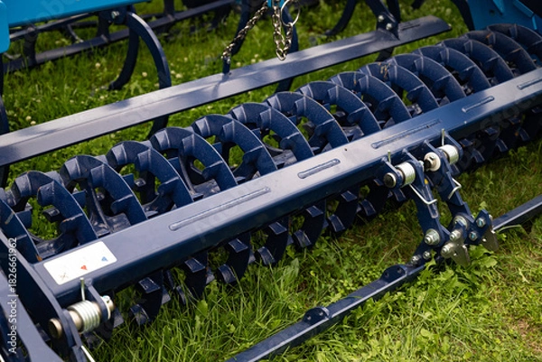 Fototapeta Agricultural machinery close-up with metal components and red frame.