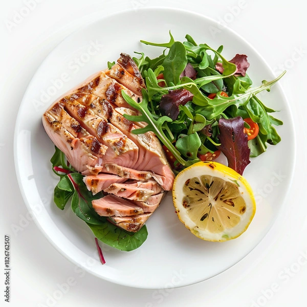 Fototapeta Perfectly grilled salmon fillet sliced and served with fresh mixed green salad and a bright lemon half, isolated on white background