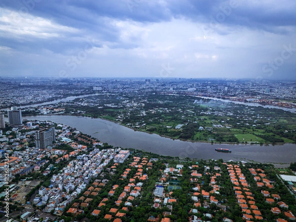 Obraz A city with a river running through it. The river is surrounded by houses and buildings. There is a boat on the river