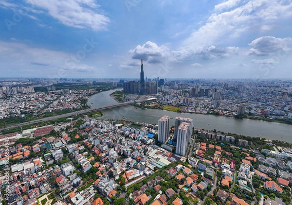 Obraz City with a river running through it. The river is surrounded by buildings. The sky is blue and there are clouds