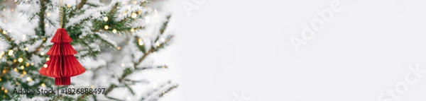 Fototapeta Minimalist Christmas tree with red paper ornament and lights on snowy background. Festive composition, layout for a New Year's card, banner